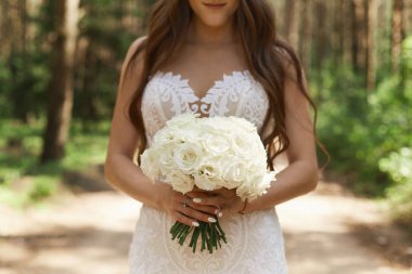 Güzel ve şık esmer model kız elinde çiçek bir buket tutan ve sabah erken saatlerde ormanda poz moda dantel elbise