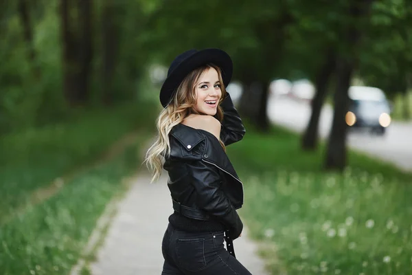 Chica sonriente feliz en chaqueta de cuero negro y en sombrero negro de moda —  Fotos de Stock