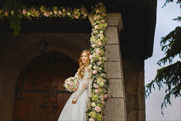 Belle et sexy mariée, la fille modèle avec coiffure de mariage dans une robe de mariée élégante tenant bouquet de fleurs près d'une ancienne église en Suisse — Photo