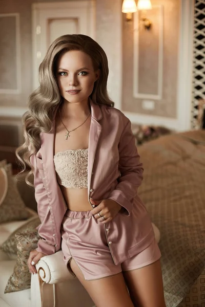 Ung blond modell kvinna med docka ansikte och bröllop frisyr i snygg sexig rosa pyjamas på klassisk amerikansk interiör — Stockfoto