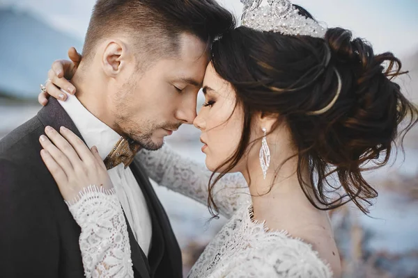 Bella coppia di amanti che si abbracciano, una giovane donna con acconciatura da sposa e gioielli di lusso e bellissimo uomo brutale in giacca e cravatta — Foto Stock