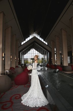 Lüks modern iç poz elinde çiçek bir buket ile şık bir gelinlik mükemmel bir vücut ile şık sarışın model gelin