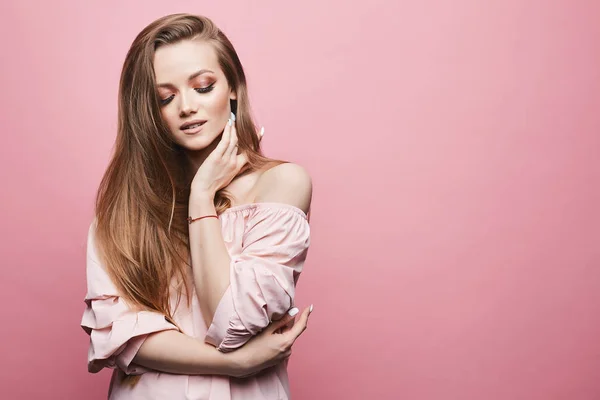 Fashionabla och förföriska blond modell flicka med ljusa professionella makeup och slutna ögon, i snygg blus med nakna axlar, isolerad vid rosa bakgrund i studion — Stockfoto