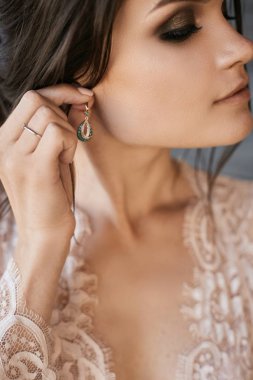 Kapalı gözleri ve parlak makyaj onu küpe ayarile güzel esmer kadın, düğün töreni için genç bir seksi gelin hazırlık