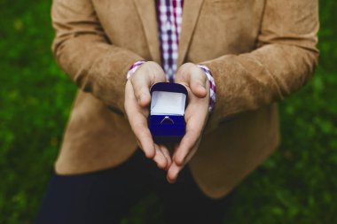 Yakışıklı genç adamın erkek elinde şık altın alyansile kutu, evlilik teklifi