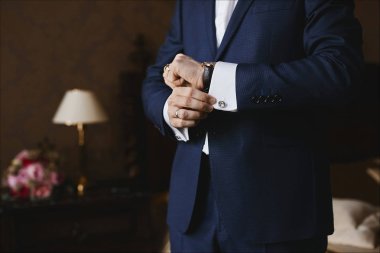 Smokinli yakışıklı bir işadamının elindeki lüks saatlerin ve kol düğmeli gömleğin yakından görünümü