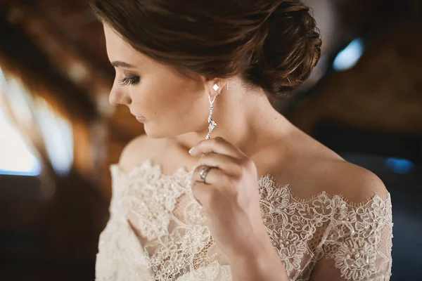 Fiatal barna szépség esküvői frizura divatos csipke ruha beállítása neki fülbevaló és pózol a belső — Stock Fotó
