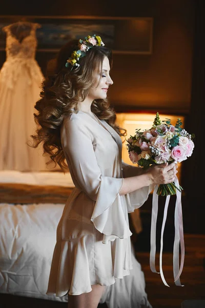 Mooie model vrouw met perfect lichaam en met bruiloft kapsel versierd met bloemen, in sexy peignoir poseren op interieur — Stockfoto