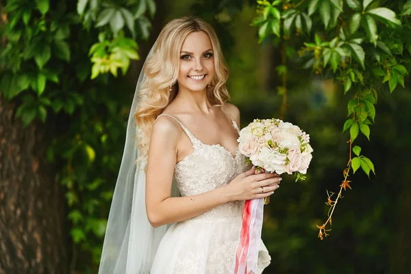 Buquê de flores frescas nas mãos da jovem mulher bonita com cabelo loiro e no vestido de noiva — Fotografia de Stock