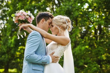 Onu düğün saç modeli lüks takı ile güzel sarışın model kadın ve şık elbise şık mavi blazer onu yakışıklı damat kucaklar ve açık poz