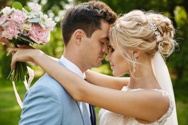 Onu düğün saç modeli lüks takı ile güzel sarışın model kadın ve şık elbise şık mavi blazer onu yakışıklı damat kucaklar ve açık poz