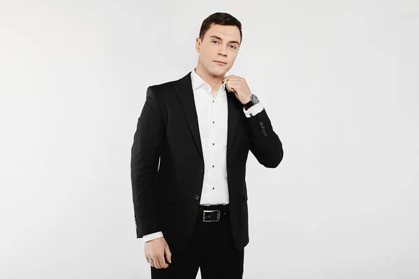 Красивый улыбающийся молодой бизнесмен в белой рубашке с запонками и в стильном черном костюме, изолированном на белом фоне — стоковое фото