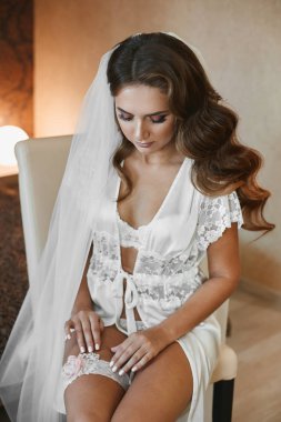 Düğün saç modeli ve şık dantel iç çamaşırı parlak makyaj ile seksi yarı çıplak esmer model kadın düğün jartiyer koyar ve bir düğün töreni için hazırlanıyor