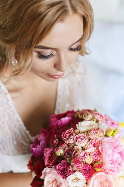 Kapalı gözleri ve şık peignoir gül ve şakayık çiçek buketi tutan seksi tam dudaklar ile güzel genç model kadın