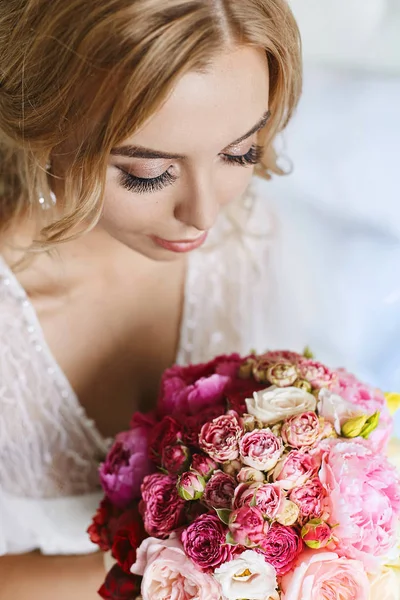 Mulher modelo jovem bonita com olhos fechados e com lábios cheios sexy em peignoir elegante segurando buquê de flores de rosas e peônias — Fotografia de Stock