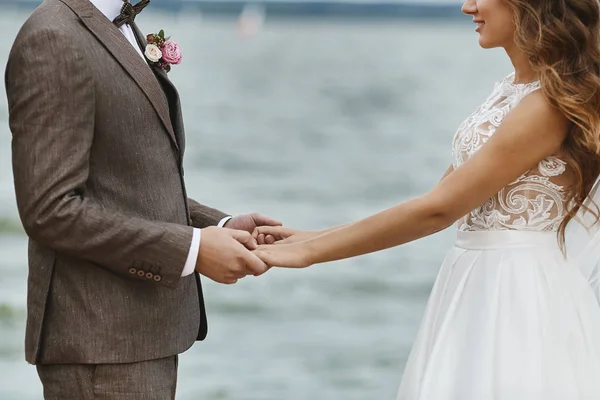 Fashionable and beautiful couple of just married holding hands at a wedding ceremony