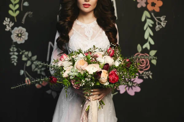 Hermosa mujer modelo morena con peinado elegante en el vestido de encaje elegante que sostiene un gran ramo de lujo de flores exóticas en sus manos, posando en el fondo negro — Foto de Stock