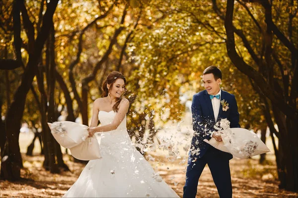 Casal bonito e feliz de recém-casado tem diversão e luta por travesseiros no parque da cidade verde no dia ensolarado de verão — Fotografia de Stock