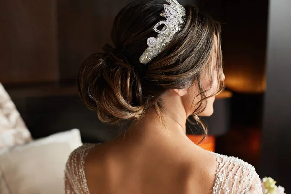 Penteado de casamento com jóias - mulher jovem modelo morena na moda em um vestido de renda e com um diadema na cabeça antes da cerimônia de casamento — Fotografia de Stock
