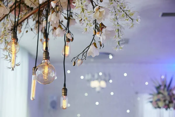 Elektrische alte gelbe Glühbirnen und frische Blumen. Dekorationen für Hochzeitszeremonien in Vintage-Umgebung — Stockfoto