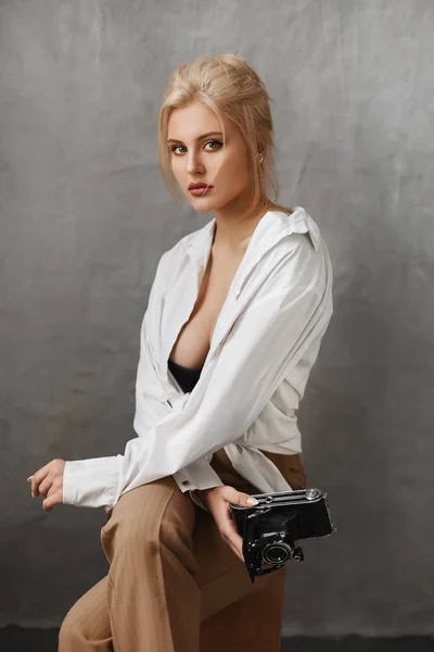 Модная блондинка в черном лифчике, расстегнутая рубашка и брюки, позирующие на сером фоне — стоковое фото