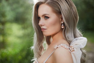 Platin sarışın Yan yakın görünümü, gelinlik güzel kadın ve elmas ile pahalı lüks küpe ile