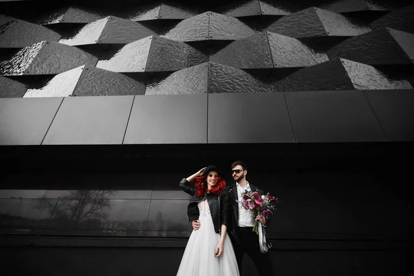 Trendy cool and brutal fiance and fashionable bride posing on the black urban background at the city street — Stock Photo, Image