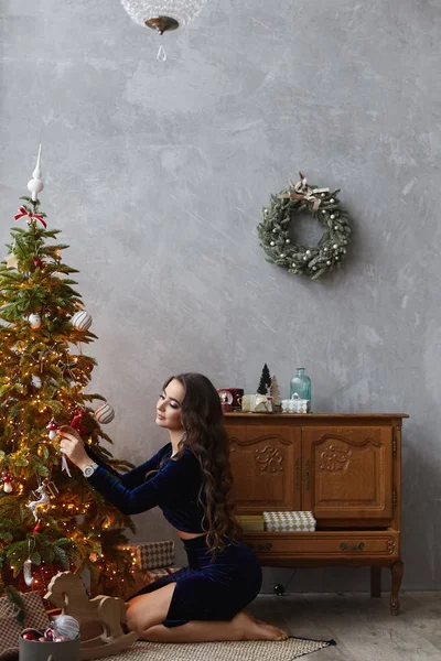 Oturma odasında Noel ağacı dekorasyon şık mavi elbise güzel ve şık esmer model kız. Yeni Yıl ruh hali.