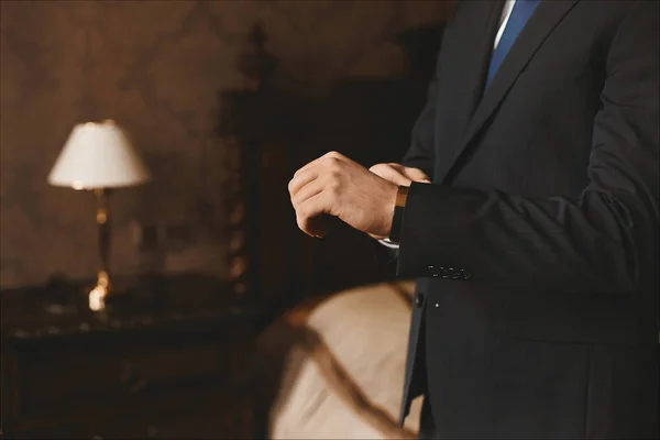 Vista cercana de las manos masculinas con relojes de lujo de joven hombre de negocios guapo en un traje elegante en la sala de estar. Concepto de estilo oficial y preparación para la reunión de negocios — Foto de Stock