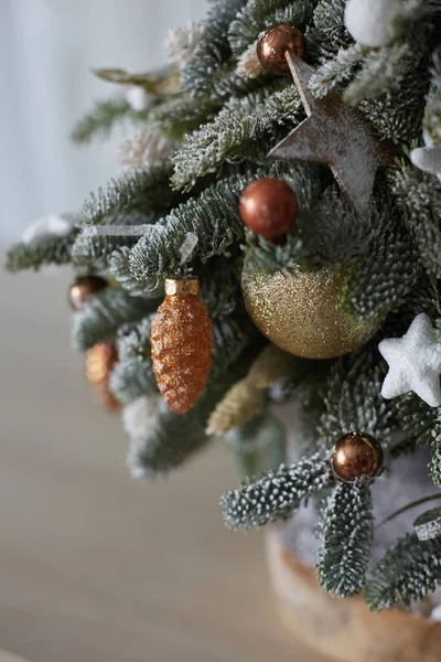 Weihnachtsschmuck auf dem kleinen Weihnachtsbaum. Kunstschnee auf Tanne, Weihnachtskugeln und Sternen. Konzept der Neujahrsferien und Dekorationen. Konzept einer Weihnachtskarte — Stockfoto