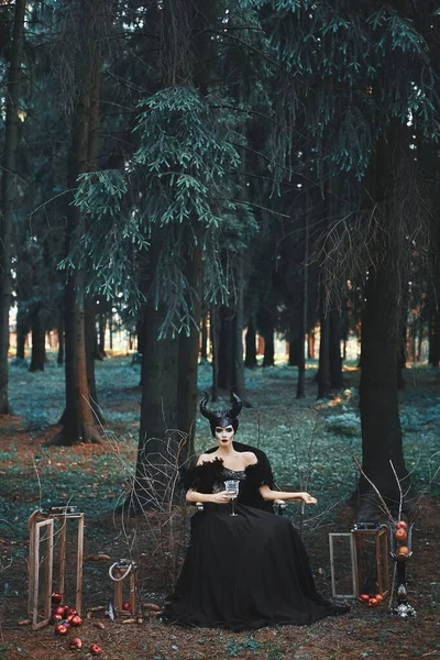 ハロウィーンのための化粧や衣装を持つ神秘的なモデルの女の子。神秘的な森の中でマレフィセントのポーズのイメージのスタイリッシュなモデルの女の子-童話、コスプレ. — ストック写真