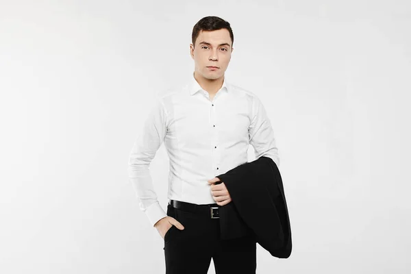 Νεαρός επιχειρηματίας με στολή casual στυλ. Ο άντρας ποζάρει με ένα λευκό μακρυμάνικο πουκάμισο με τζιν και κρατά ένα σακάκι στο χέρι του. Έννοια της ανδρικής μόδας. — Φωτογραφία Αρχείου