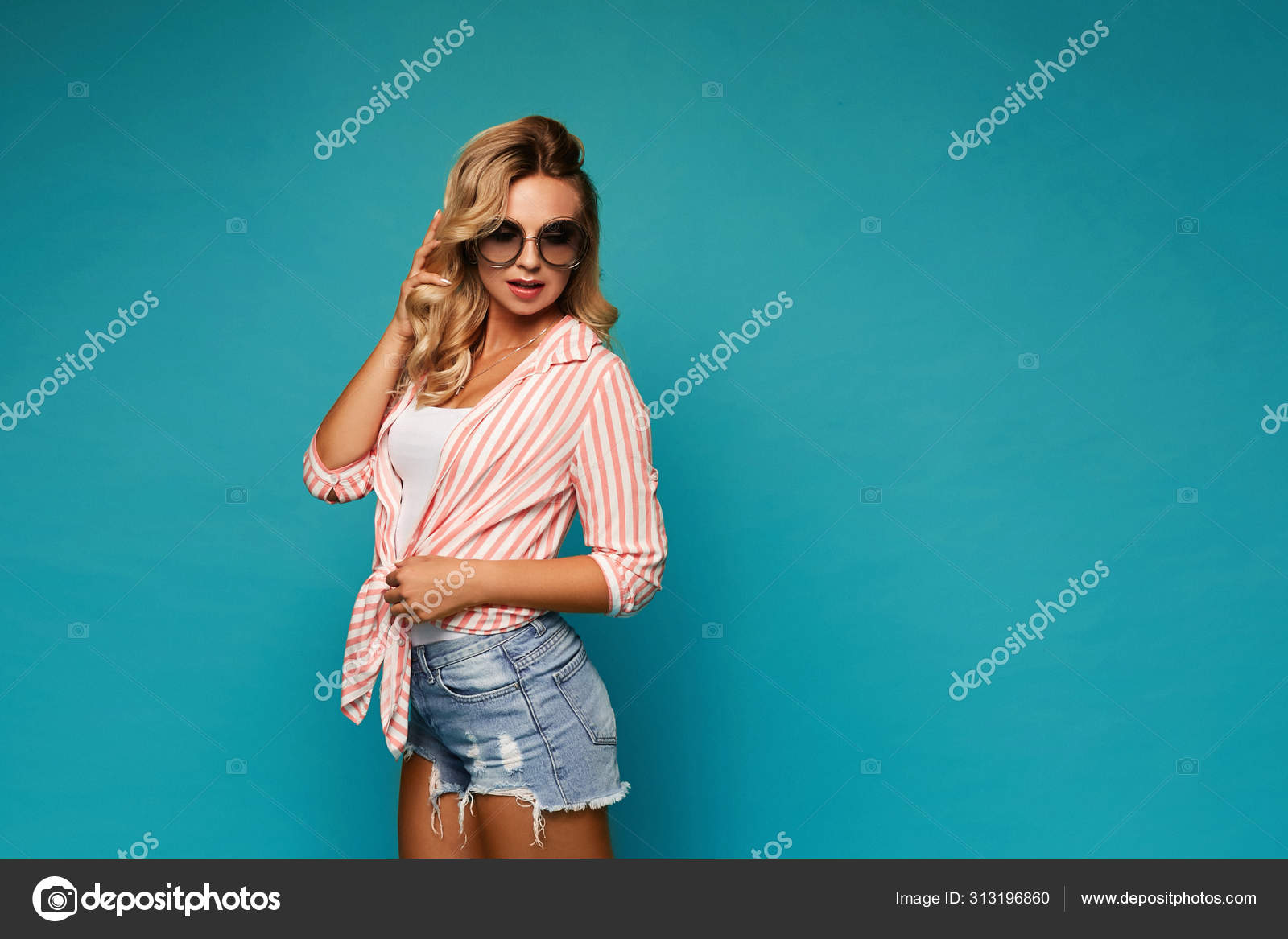 Young seductive woman in sunglasses, jeans shorts and a striped shirt