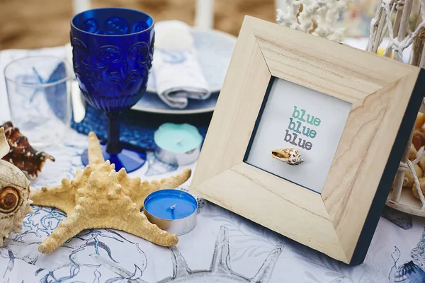 Hochzeitsdekoration im maritimen Stil - Tisch für Braut und Bräutigam an einem Sandstrand mit Muscheln, Korallen, Kerzenlicht und Weinglas — Stockfoto