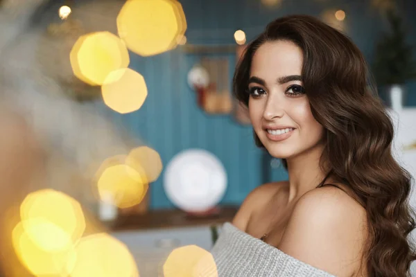 Menina modelo morena bonita com maquiagem brilhante e penteado modish posando no interior do Natal. Uma jovem mulher em vestido de lã posando na cozinha. Humor de Ano Novo. Conceito de véspera de Natal . — Fotografia de Stock