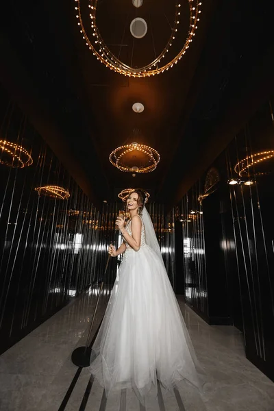 Hermosa chica modelo piernas largas en vestido de novia manteniendo el micrófono de oro y cantando en un restaurante de lujo. Mujer alegre disfrutando del día de la boda y la celebración . — Foto de Stock