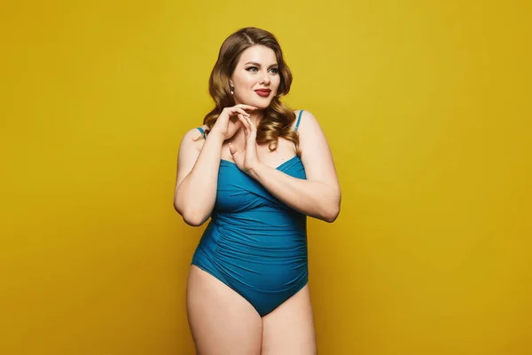 Plus-size model girl in swimsuit isolated at the yellow background. Fat woman in swimsuit on yellow background. Pin-up style photo. Copy space to advertise — Stock Photo, Image