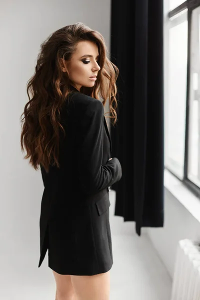 Jonge sensuele sexy vrouw met trendy kapsel in modieuze zwarte jas-jurk poseren in witte achtergrond — Stockfoto