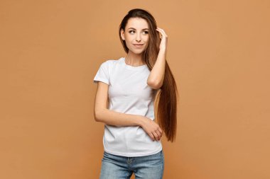 Beyaz gömlekli ve kot pantolonlu bej arka planda, izole edilmiş genç bir kadın. Sıradan kıyafetli manken kız. Model