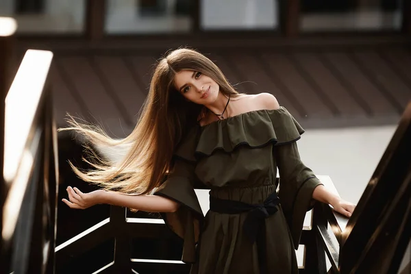 Mladá žena s brunetovými vlasy v tmavozelených šatech pózující na střeše — Stock fotografie
