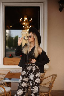 Genç hippi kız şehirdeki bir kafede şarap içiyor.