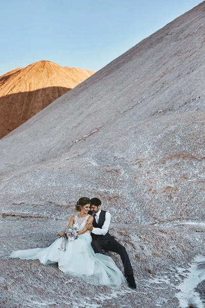 A young couple of newlyweds hugging and posing outdoors over the beautiful landscape with mountains — Stock Photo, Image