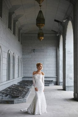 Şık bir gelinlik içindeki genç gelin yaz günü dışarıda poz veriyor.