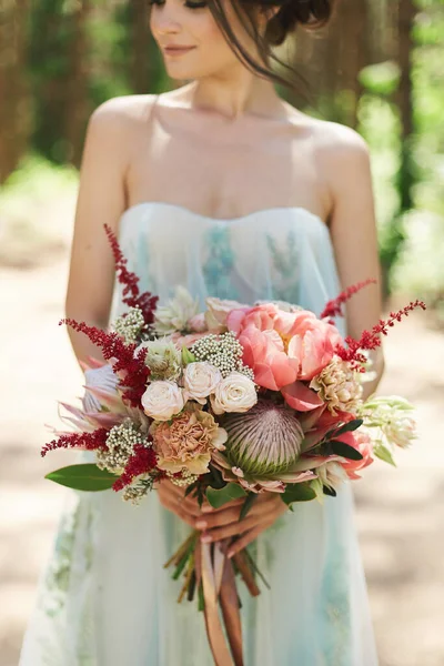 Bouquet de fleurs exotiques entre les mains d'une jeune fille modèle en robe d'été — Photo