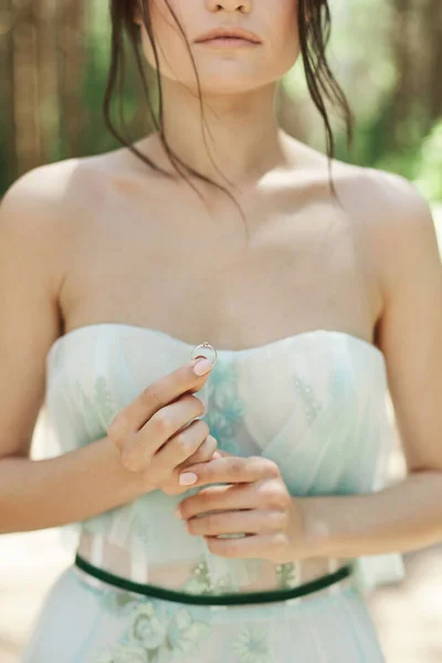 Brunette model girl in a stylish dress keeping the bridal ring in her hand outdoors — Stock Photo, Image