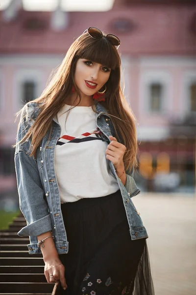 Modèle fille de race mixte avec maquillage lumineux et lèvres rouges regardant dans la caméra et posant à l'extérieur — Photo