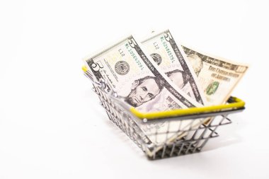 Amerikan parası (dolar) beyaz arka planda küçük bir market sepetindedir..