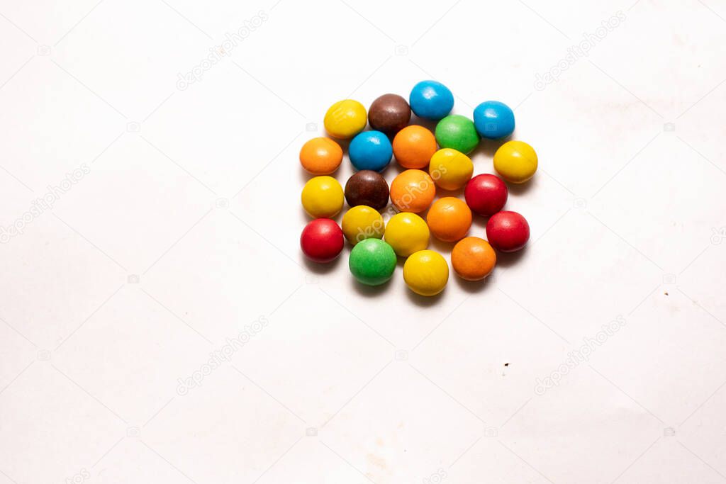 chocolate candies in multi-colored glaze on a white background. sweets. space for text