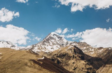 Gürcistan'daki güneşli havalarda kar altında yüksek bir dağın zirvesine