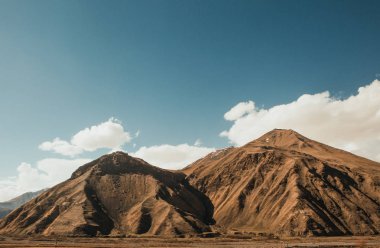 yol boyunca beyaz bulutlar ile yüksek dağları